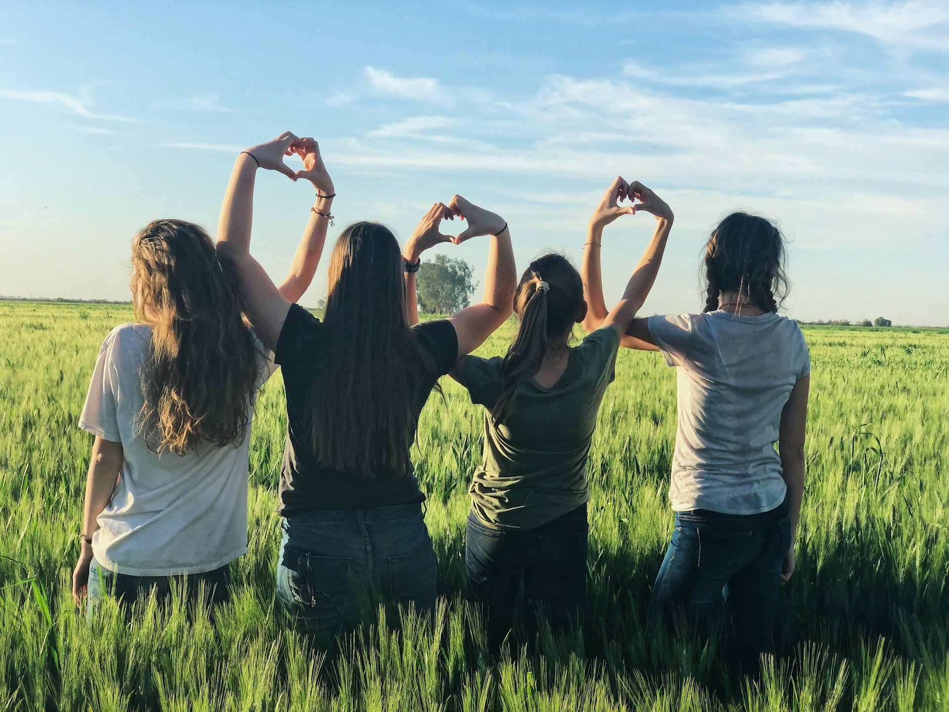 Un grupo de amigos haciendo corazones con las manos en un campo.