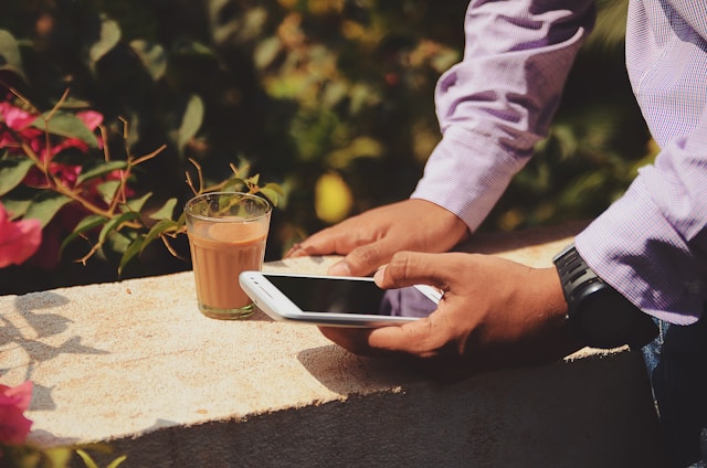Persona interactuando con el teléfono mientras toma un café.